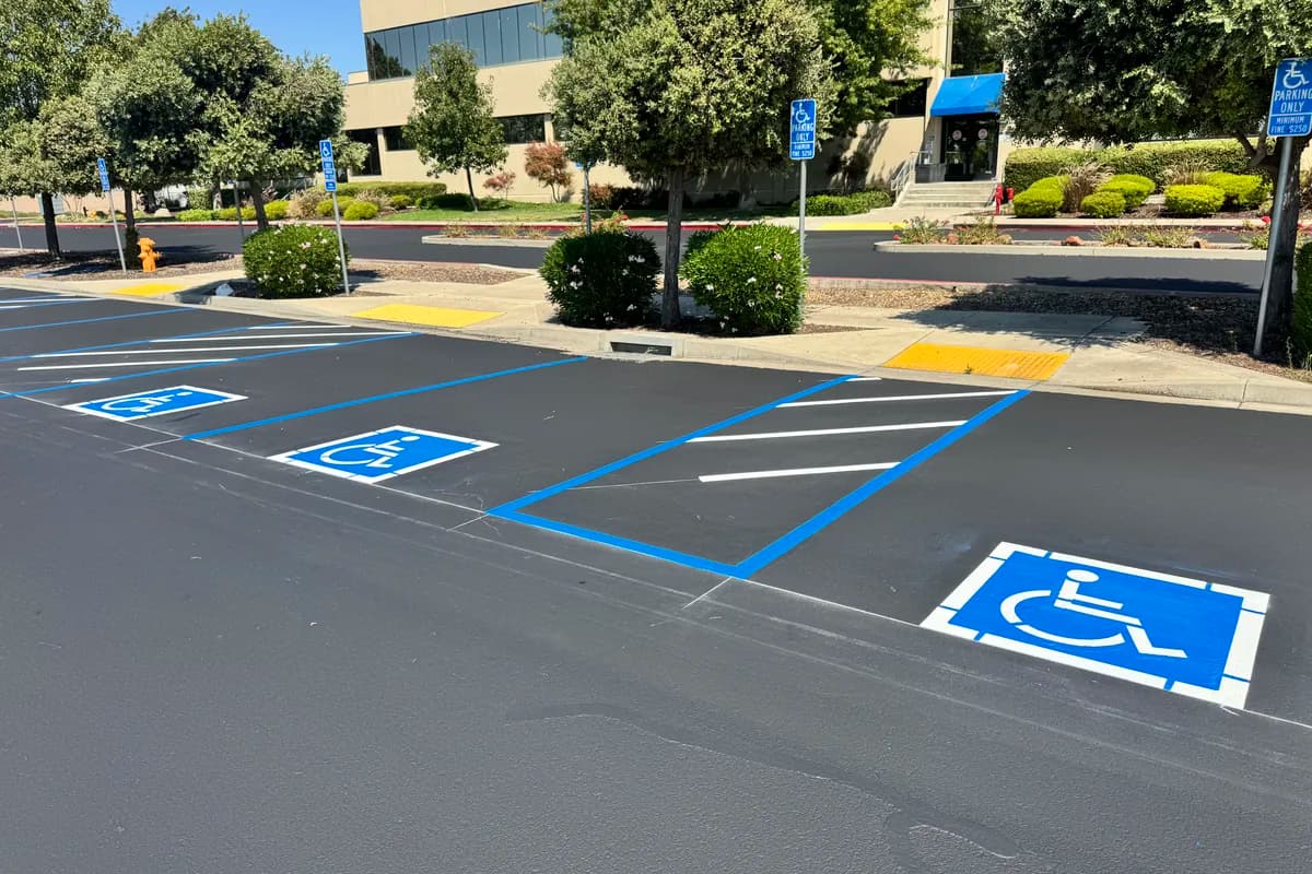 Accessible parking stall with blue ADA striping, access aisle, and signage in front of a commercial building.