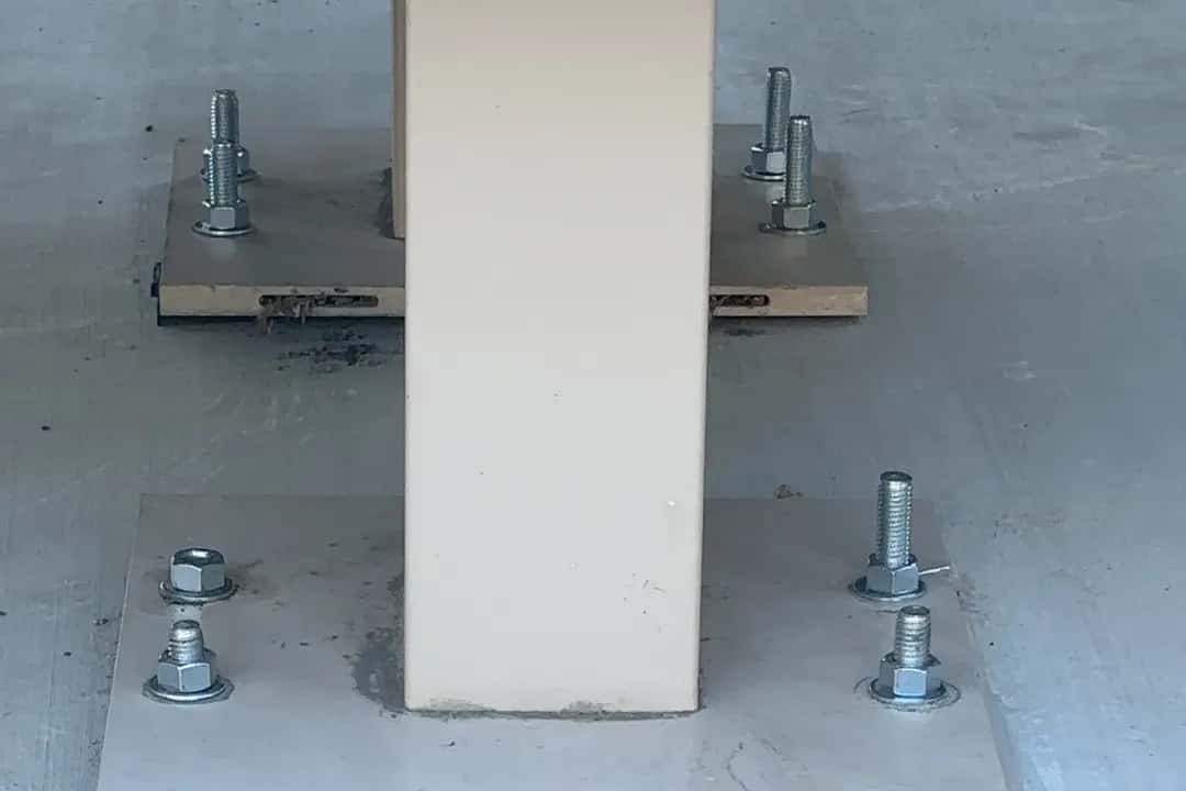 Steel base plates bolted to a new concrete pad with anchor studs and levelling nuts