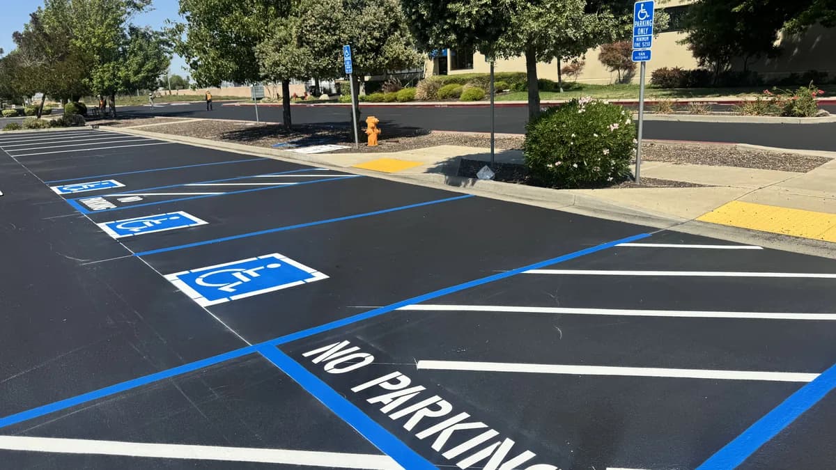 Freshly striped accessible parking stalls with blue access aisles, 'No Parking' markings, and van-accessible signage at a commercial building.