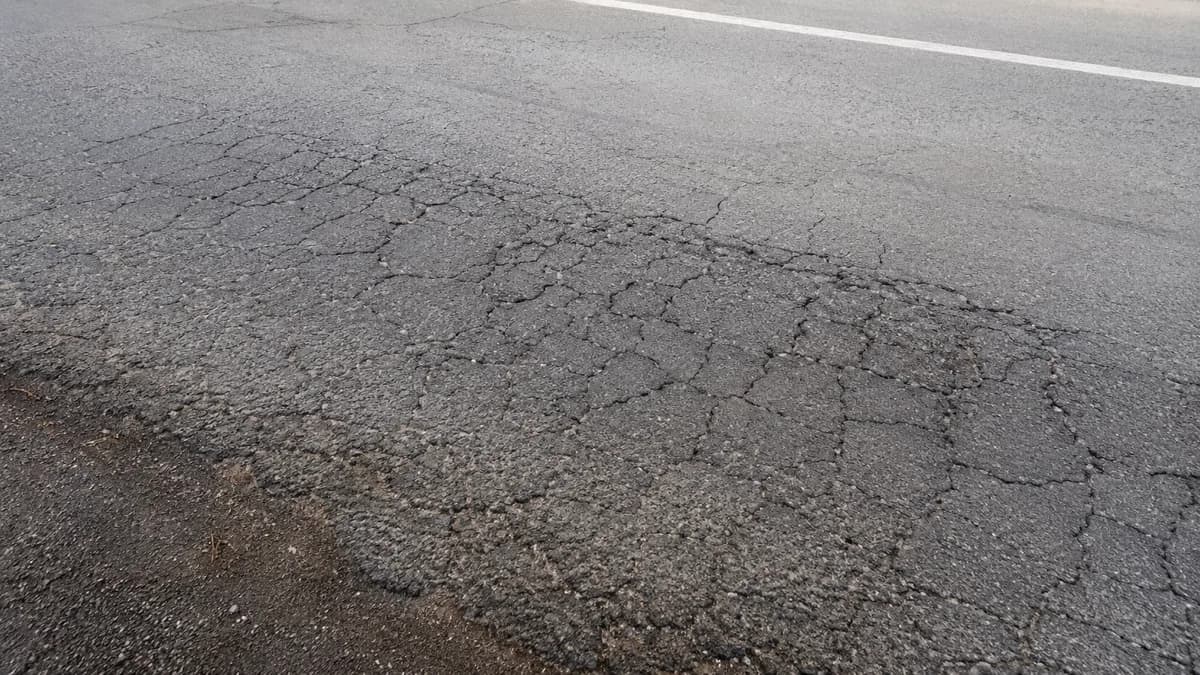Close-up of alligator cracking pattern in deteriorated asphalt pavement.