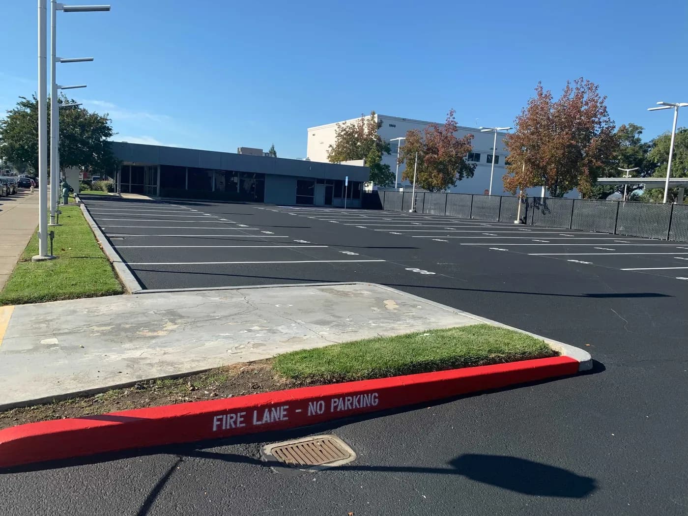 A finished commercial parking lot with a dark new asphalt surface and fresh white stall striping