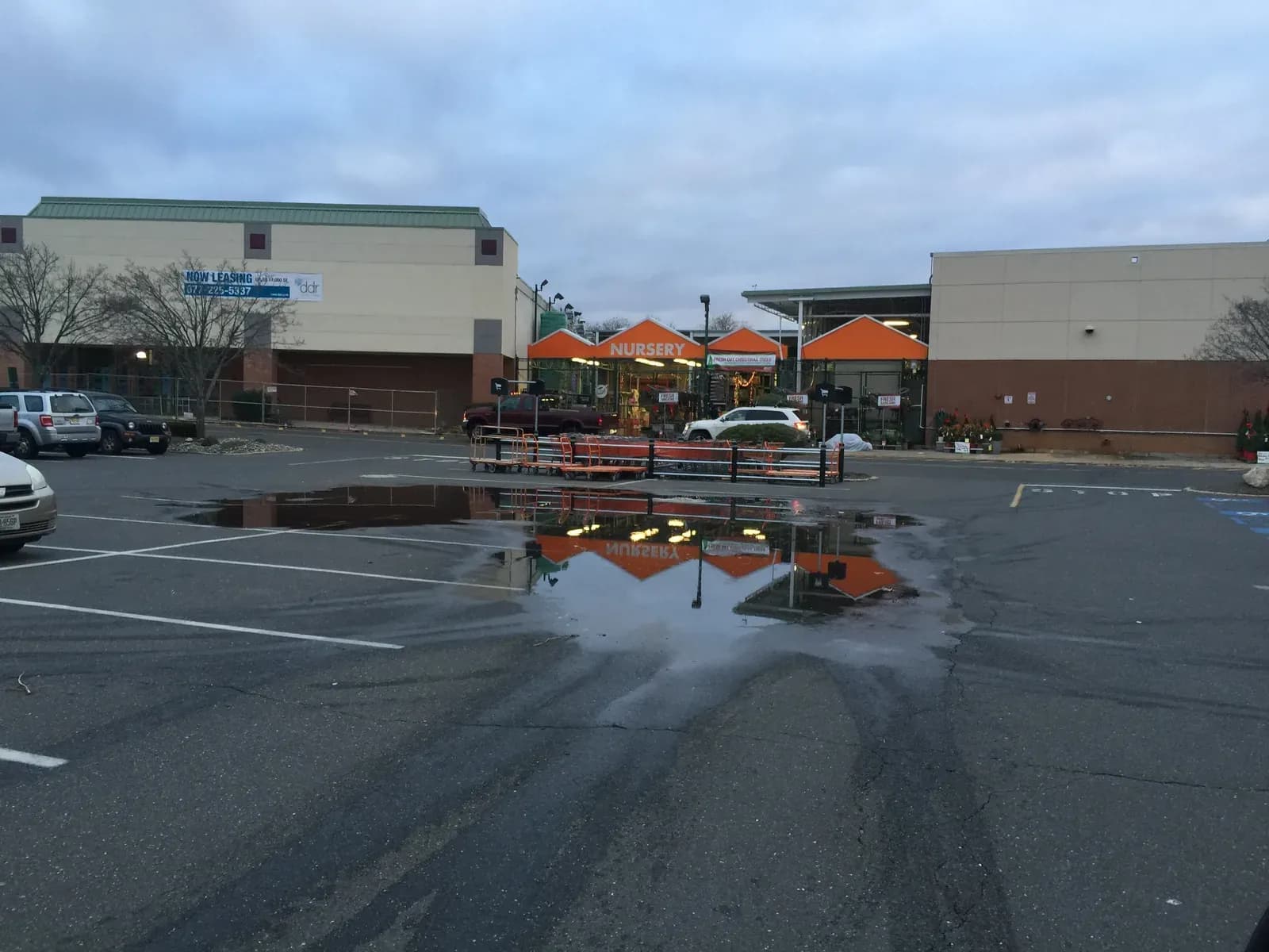 A broad sheet of standing water across a commercial parking lot the day after rain