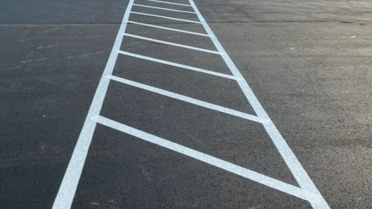 Freshly painted parking lot stalls and a directional arrow on dark asphalt.