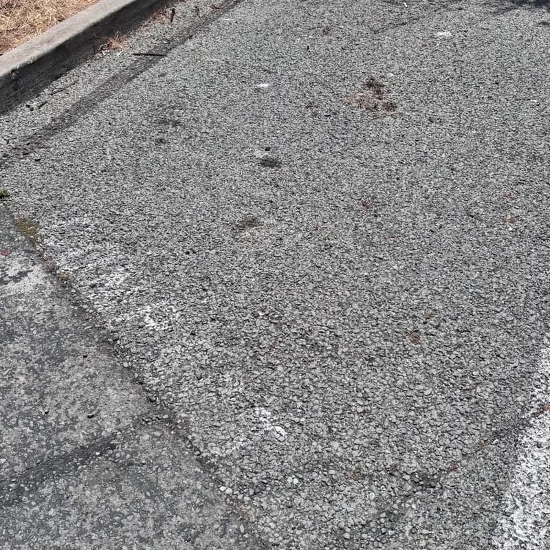 Raveled asphalt where the binder has worn away, leaving loose exposed aggregate